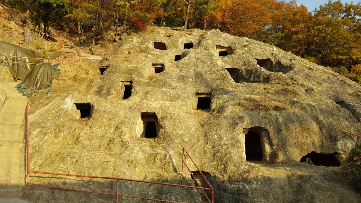 「吉見百穴」の存在は、江戸時代以前から不思議な穴として知られていましたが、一体何なのかは知られておらず明治20年（1887年）に行われた発掘調査によって徐々に、全貌が見えてまいりました。　それでも当初は、小さい穴為、日本の先住民族コロボックルの住居なる珍説を真面目に議論されたそうです。　その後も研究が進み、現代では集合墳墓という説が定説となっております。